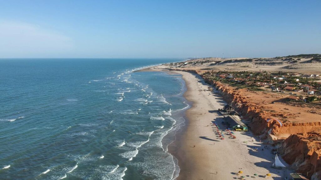 A vila colorida no alto das falésias que virou símbolo do turismo com mar esverdeado e noites cheias de vida