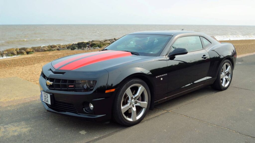 Chevrolet Camaro preto a beira da praia