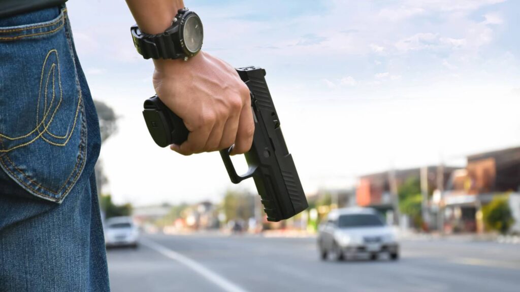 Policial a beira da pista com arma em punho