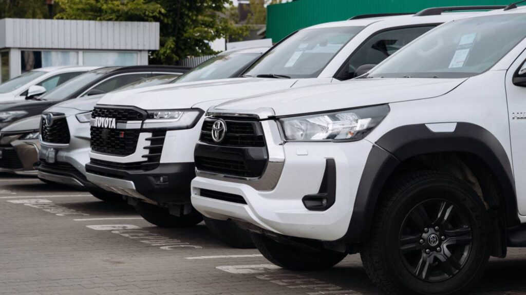 Toyota Hilux branca em fila de carros estacionados