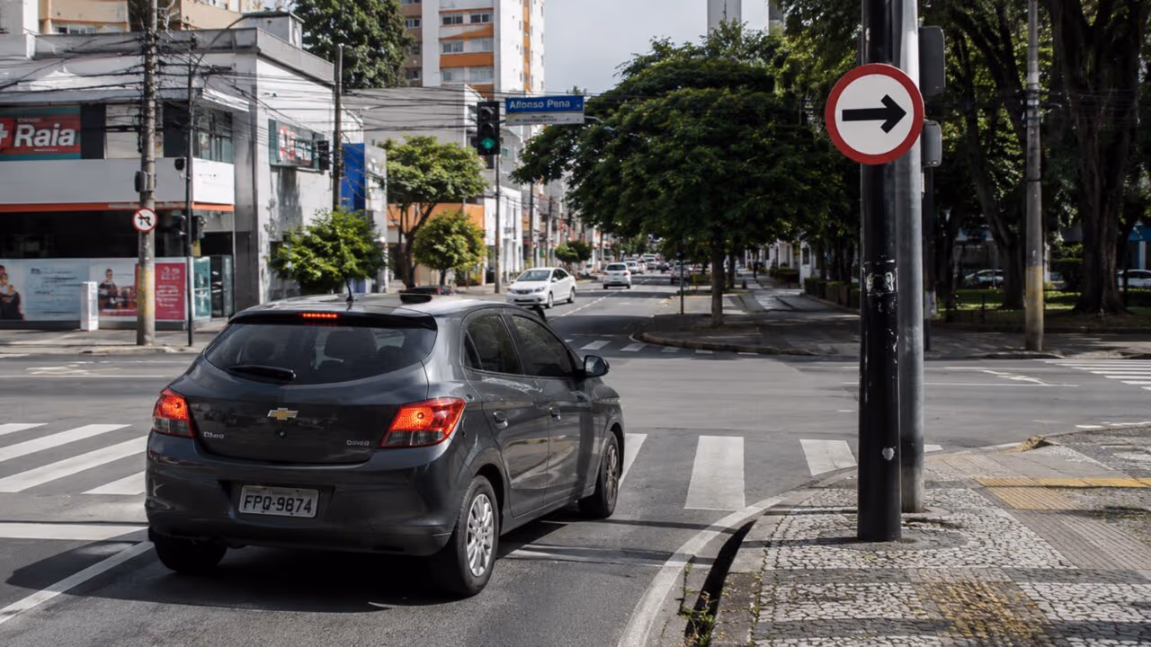 O que significa a placa de trânsito com borda vermelha, fundo branco e uma seta apontada para a direita?