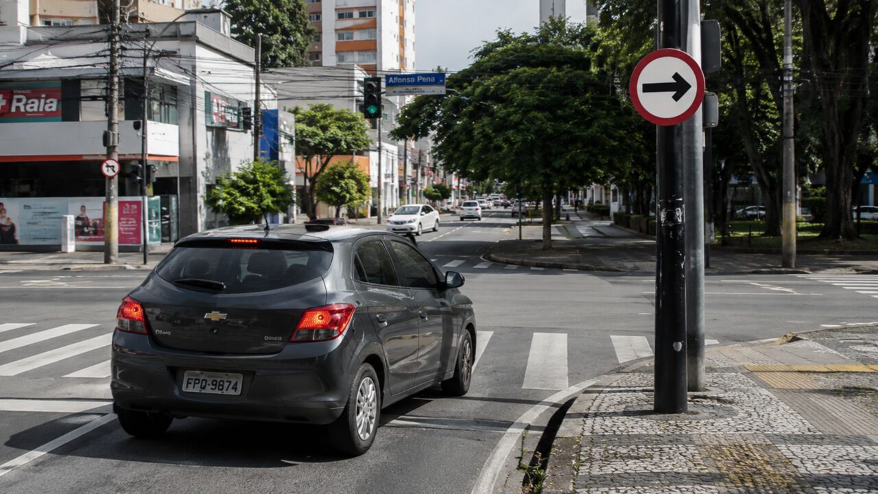 O que significa a placa de trânsito com borda vermelha, fundo branco e uma seta apontada para a direita?