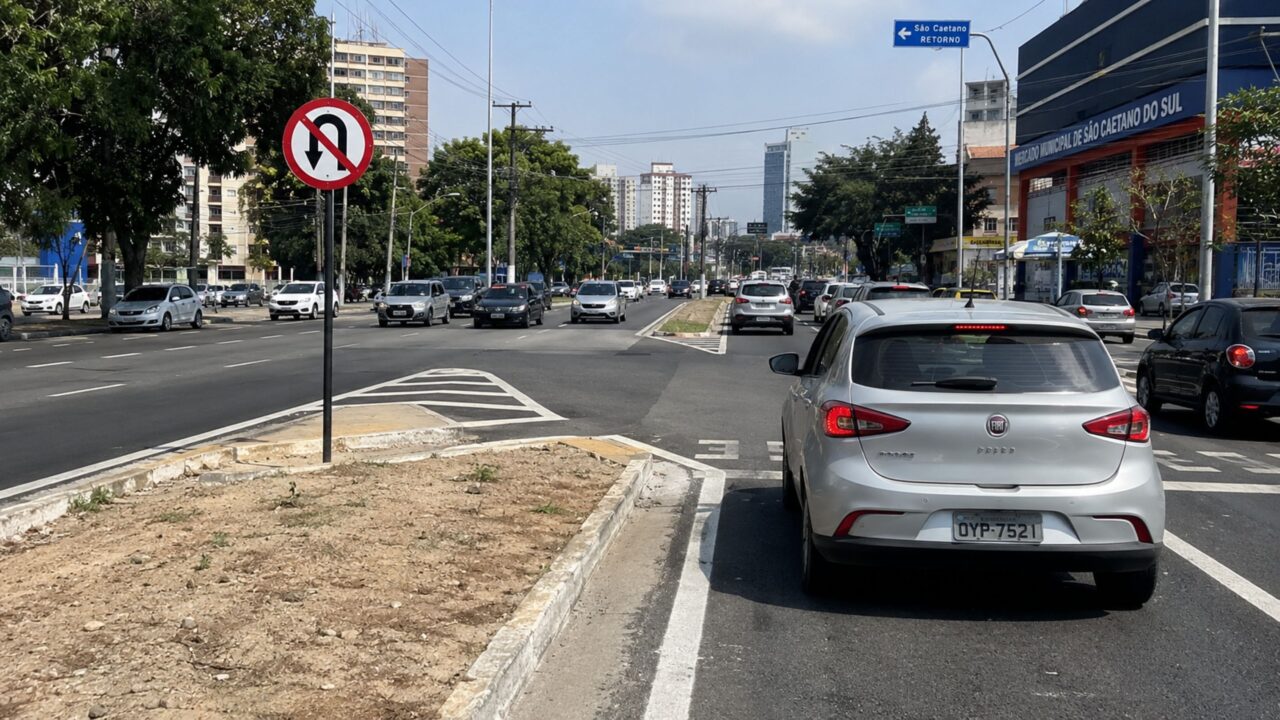 O que significa a placa de trânsito com fundo branco e uma seta curvada para baixo?