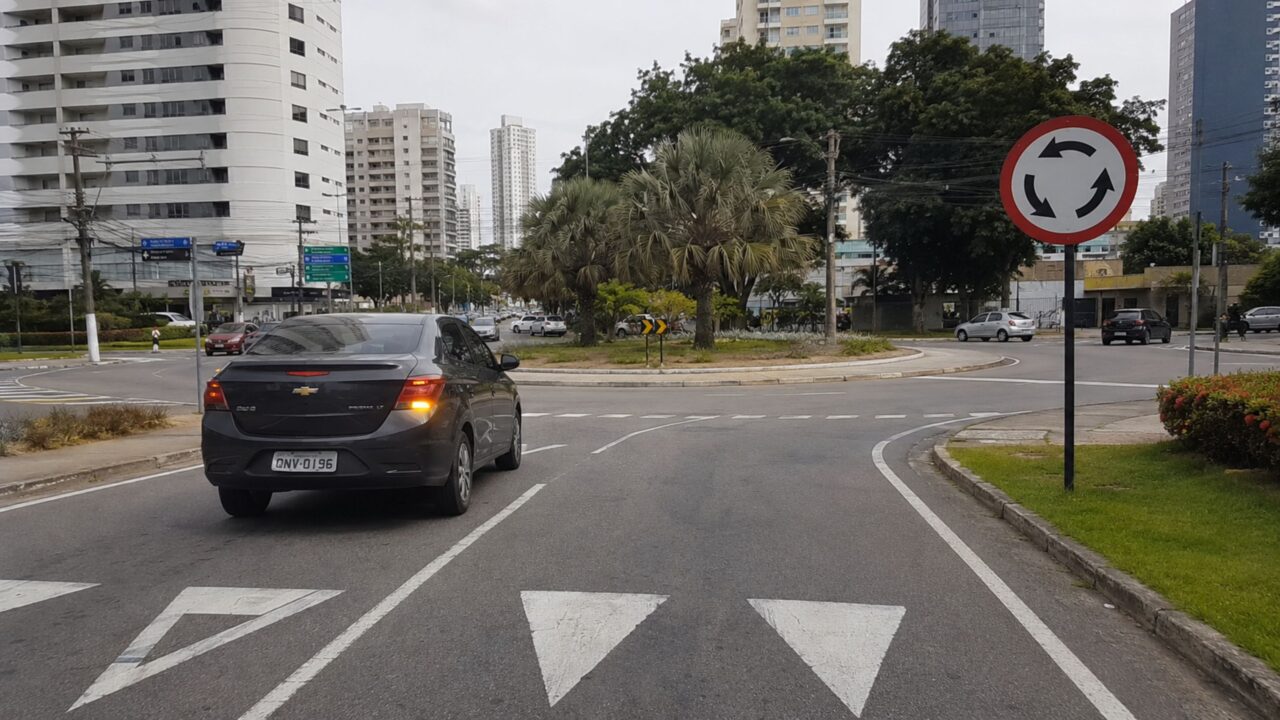 O que significa a placa de trânsito com fundo branco e 3 setas em sentido circular?