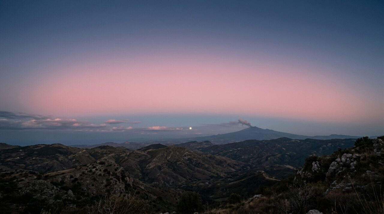O Cinturão de Vênus forma uma faixa rosada acima da sombra da Terra enquanto a pluma do Etna se destaca no horizonte siciliano