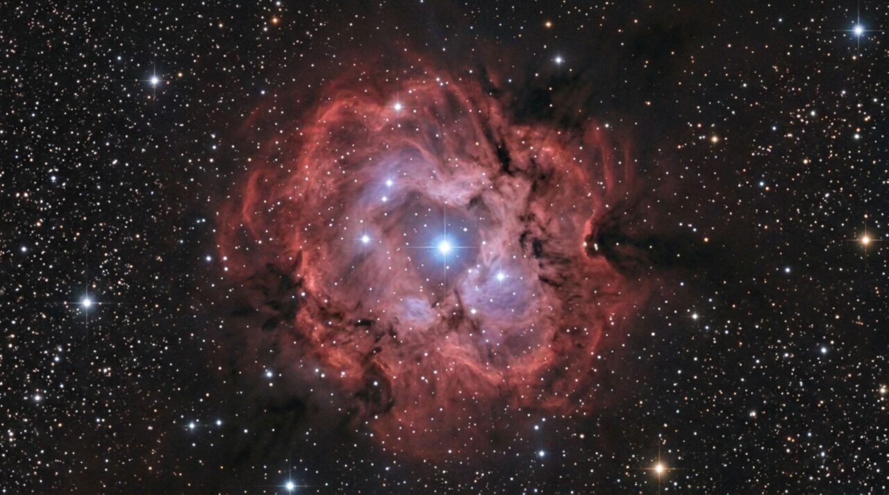 O brilho avermelhado da IC 5146 resulta principalmente do hidrogênio ionizado por estrelas jovens, enquanto a poeira interestelar cria regiões escuras e reflexos azulados