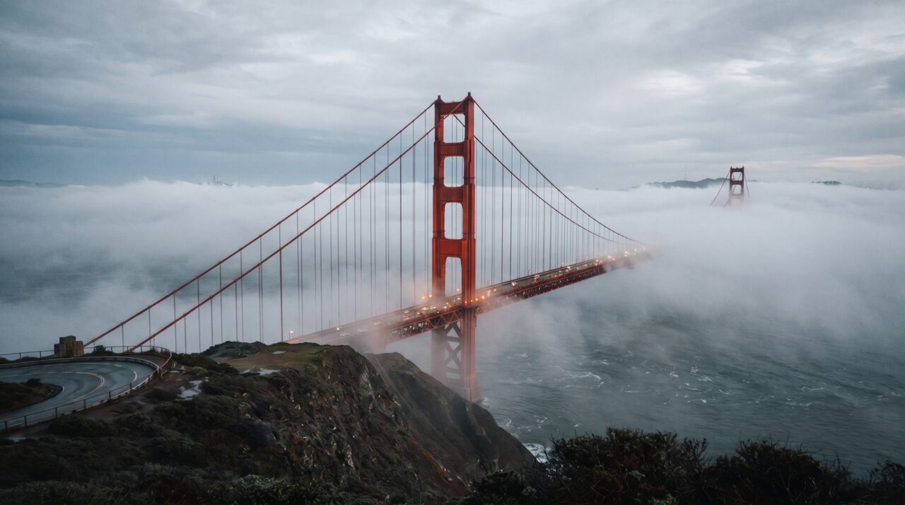 Suspensa por dois cabos principais colossais que contêm mais de 129 mil quilômetros de fios de aço galvanizado, a icônica ponte pênsil vermelha de 2,7 quilômetros foi erguida desafiando as névoas e correntes brutais do Pacífico