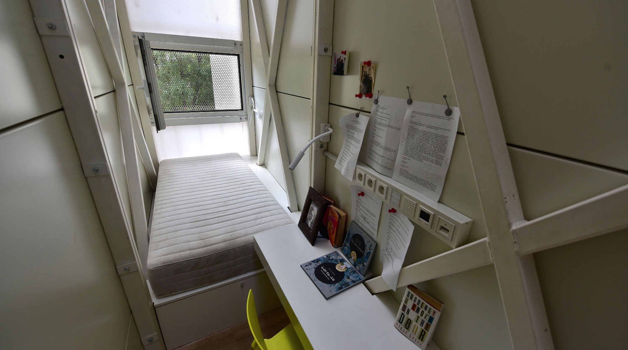 Interior da Keret House, em Varsóvia, com a cama, a escrivaninha e a janela no espaço estreito
